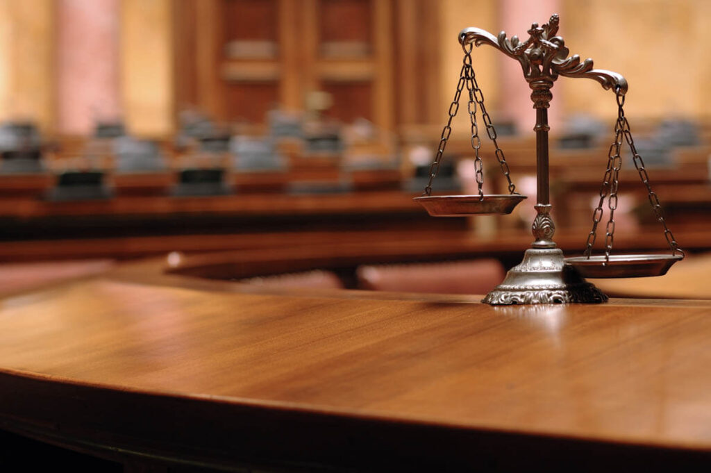 scales of justice on wooden courtroom table