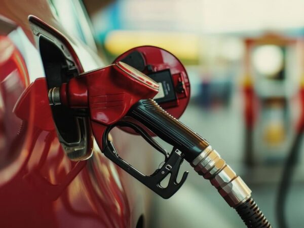 gas pump nozzle fueling red car closeup