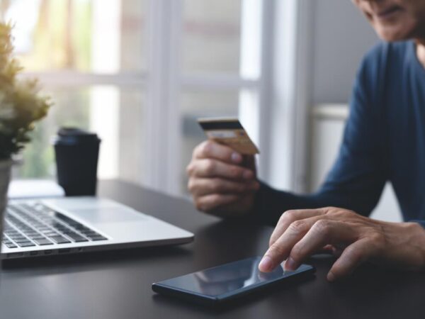 person paying online bill credit card smartphone laptop